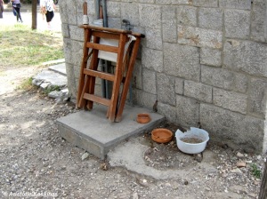 Bowls of food and water next to a the folded guard's chair behind a guard's post in an archaeological site.